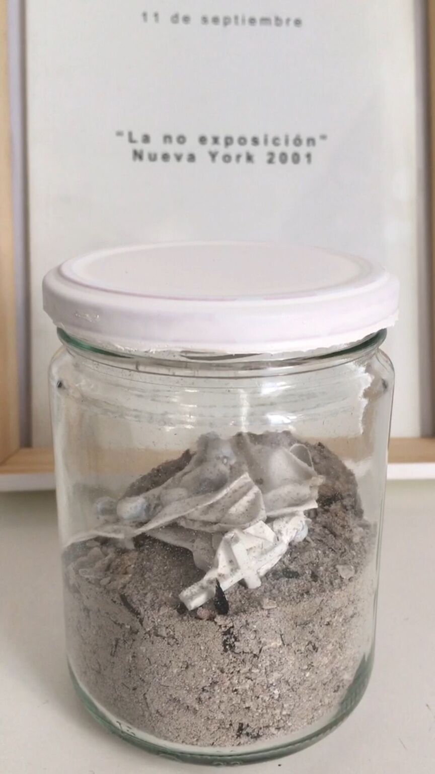 Instalación de cenizas by José Cosme, glass vessel containing ashes and fragments of paper
