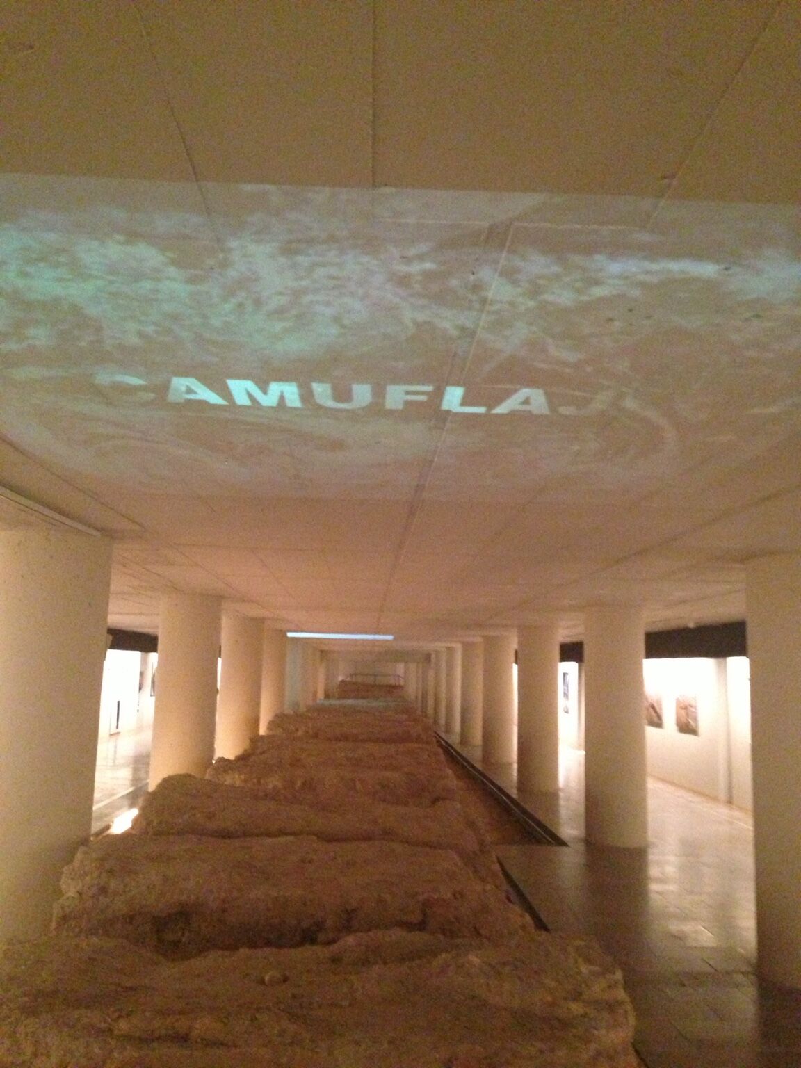Ser y Huella by José Cosme, gallery passage with earth installation and projected image